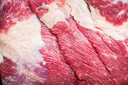 新鲜未煮过的生肉牛胸肉，在黑色木桌背景上，俯视平躺