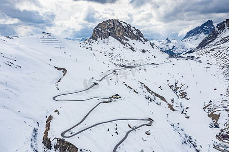 著名的地方摄影照片_意大利山区蜿蜒的道路鸟瞰图，在白雪覆盖的群山中蜿蜒曲折，是滑雪者和粉丝中著名的地方，可以了解跑车、山峰