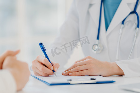 无法辨认的女医生在剪贴板上写下，为病人开处方，记录数据进行分析，穿着白色长袍。