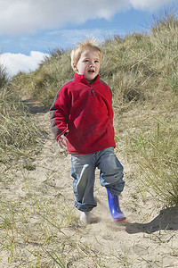 全长快乐的小男孩走在沙滩上的沙滩上