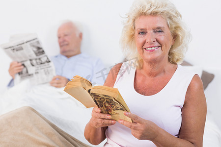 微笑的老夫妇阅读书籍和报纸
