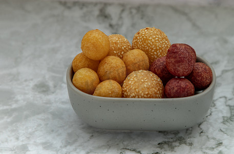 大理石桌上的芝麻炒红薯球和深炸紫色和黄色红薯球（鹌鹑糖蛋）。