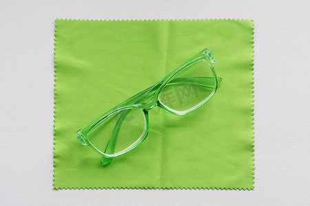 框架眼镜摄影照片_清洁布上的绿色眼镜。