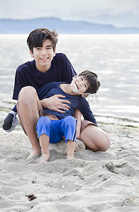 大哥抱着残疾男孩在沙滩上
