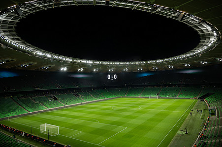 一个开放的足球场，看台上空荡荡的，座位是绿色的。