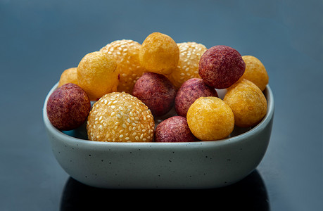 大理石桌上的芝麻炒红薯球和深炸紫色和黄色红薯球（鹌鹑糖蛋）。