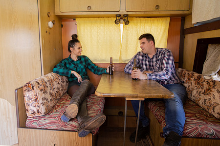 露营桌子摄影照片_年轻夫妇坐在露营车的桌子旁谈论某事