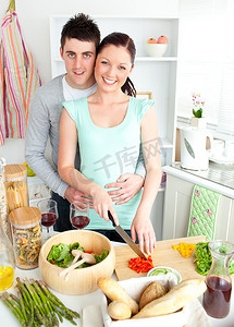 倾心的年轻夫妇在厨房里切菜