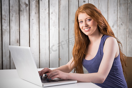 在笔记本电脑上工作的漂亮红发女郎的合成图像