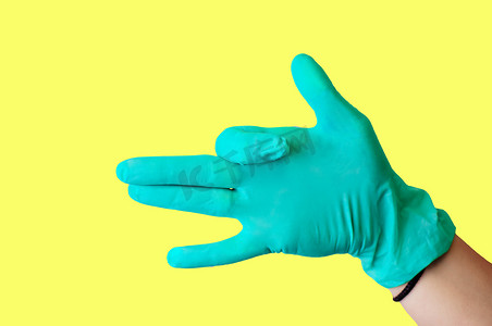 戴着蓝色乳胶手套的女手做出类似狗的手势，嘴巴张开，与淡黄色背景隔离开来。