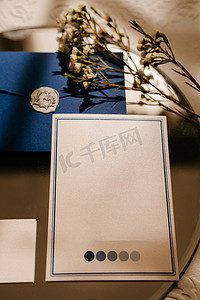 一张灰色信封里的结婚请柬，放在一张桌子上，上面放着绿色的小树枝