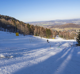 冬天晚安摄影照片_冬天在德国滑雪胜地 Lausche Waltersdorf，一位滑雪者和鸟瞰村庄，下午晚些时候