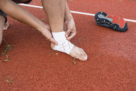 足球分组摄影照片_男子将加压绷带应用于足球脚踝损伤