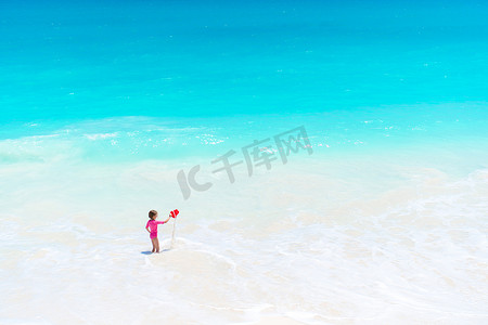 玩玩具的小女孩摄影照片_热带白色海滩的小女孩玩玩具玩得很开心