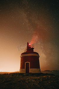 夜间灯塔的水平拍摄，背后是银河