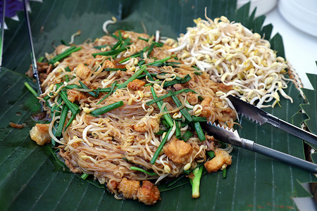 中部地区摄影照片_Korat Pad Mee是泰国呵叻府的一道本地菜，在香蕉叶上看起来和中部地区的Pad Thai很像，旁边放了一个不锈钢钳子。