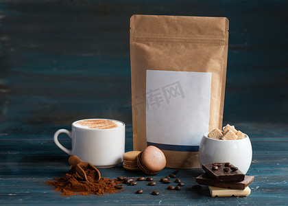 木质背景中的咖啡、咖啡豆、糖、牛皮纸袋、蛋白杏仁饼干和巧克力