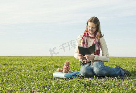 坐在草地上看电子书的女孩