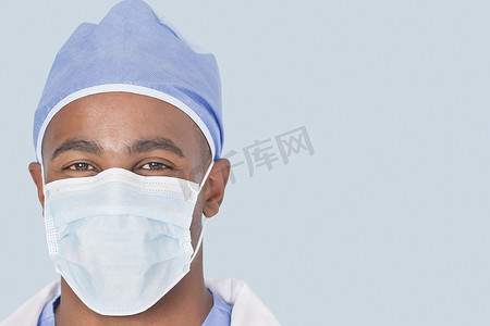 浅蓝色背景下戴面具的男性外科医生的特写