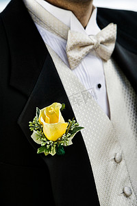 新郎燕尾服上黄玫瑰的特写照片