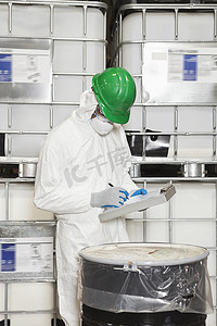 穿着防护服的技术员记下桶中的化学品