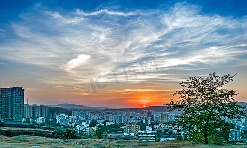 印度马哈拉施特拉邦浦那快速发展的城市高楼后面的日落。