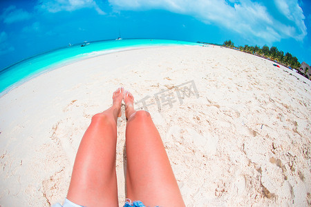 晒被摄影照片_在白色沙滩热带海滩的女性被晒黑的苗条的腿