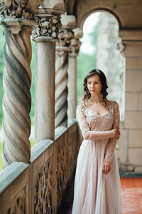 中世纪城堡背景下穿着浅粉色连衣裙的女孩
