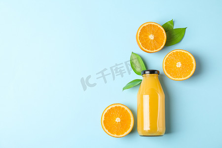 创意式摄影照片_平躺式组合物，瓶装新鲜橙汁，橙子有彩色背景的叶子，文字空间。