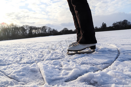 紧靠穿着滑冰靴站在冰上的女人脚。