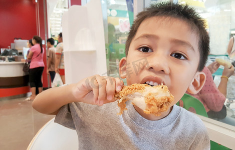 炸鸡腿摄影照片_亚洲男孩吃炸鸡。