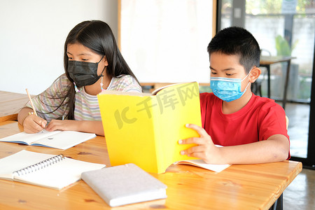 女孩男孩学生戴着口罩学习写笔记做作业。