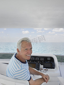 坐在豪华游艇掌舵的微笑的中年男子