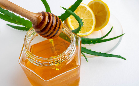 在白色背景下增强免疫系统的有用成分。罐装蜂蜜、柠檬和芦荟。