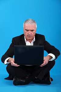 高级商人坐在地板上，带着笔记本电脑