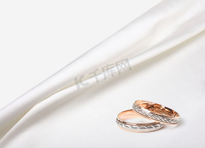 丝绸邀请函摄影照片_白色丝绸背景上的结婚戒指