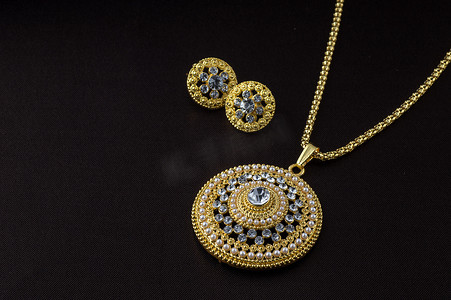 黄金珠宝摄影照片_印度传统珠宝，深色背景下垂饰的特写