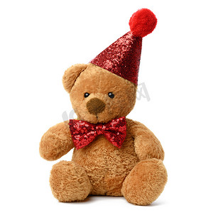 可爱系摄影照片_可爱的泰迪棕熊戴着红色喜庆的闪亮帽子，脖子上系着领结