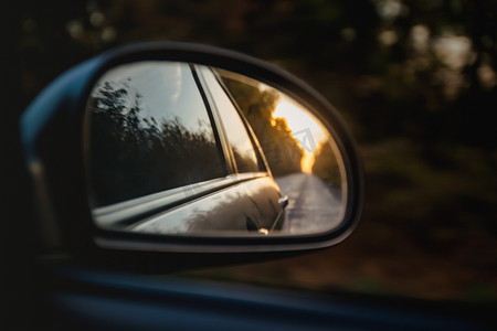 日落阳光下道路的反射在汽车的后视镜中变得模糊。
