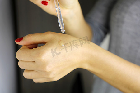应用要素摄影照片_女性手滴血清胶原蛋白保湿霜。