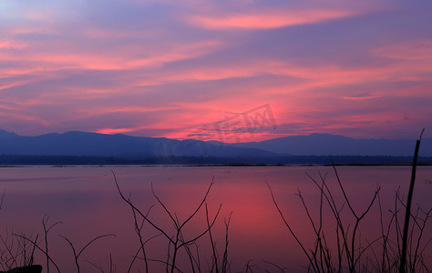 蓝色湖水摄影照片_在湖的日落剪影树