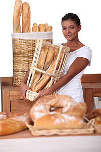长提摄影照片_面包店里提着一篮法式长棍面包的年轻女人