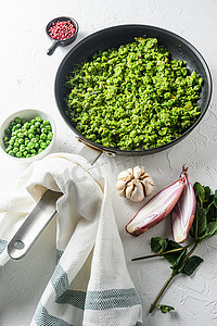 自制糊状豌豆煮熟的煎锅和碗中的豌豆，在白石表面有机酮食品侧视图上加薄荷葱胡椒和盐