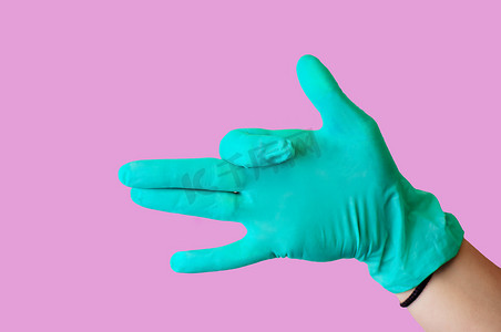 戴着蓝色乳胶手套的女手做出了一个类似于张开嘴巴的狗的手势，与浅粉色背景隔离开来。