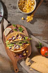 大肠面炸酱面摄影照片_传统的墨西哥炸玉米饼，木桌上有鸡肉和蔬菜。