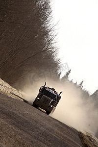 灰尘的旅行摄影照片_冬天在狭窄的道路上接近卡车