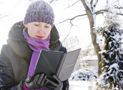 冬季在户外看电子书的年轻女士