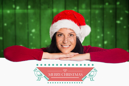 戴着圣诞帽的微笑女人靠在标语牌上，上面写着圣诞问候