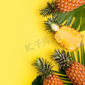 既往开来再创辉煌摄影照片_热带棕榈蒙斯特拉叶上的美丽菠萝与明亮的淡黄色背景、顶视图、平躺、头顶上方的夏季水果隔离开来。