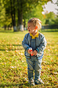 .小男孩因为在秋天的公园里洒了肥皂泡而哭泣